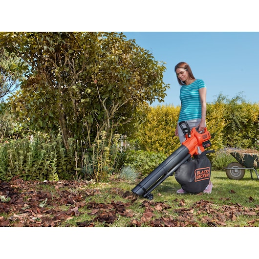 BLACKDECKER BCBLV36B leaf blower vacuum with collection bag in use in a garden.