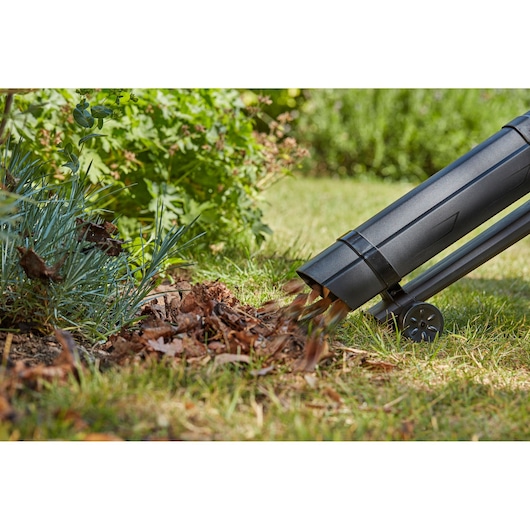 BLACKDECKER BCBLV36B garden vacuum discharging mulch on grass, side view outdoors.