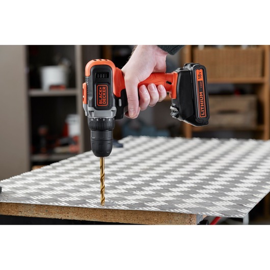 BLACK+DECKER BCD002C2K cordless drill in use drilling into metal sheet, close-up side angle.