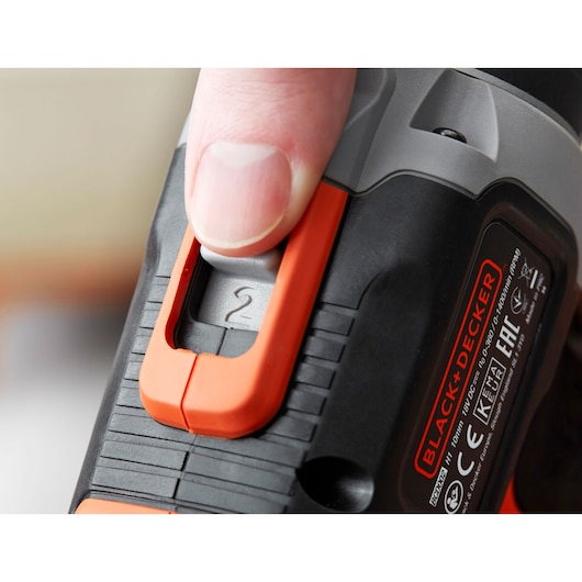 Close-up photo of a hand adjusting the speed switch on a BLACK+DECKER drill BCD003C1, showing brand label.