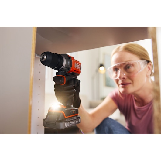 BLACKDECKER BCD382D1 cordless drill with LED light used on furniture assembly, close-up view.
