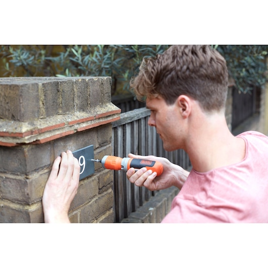 BLACKDECKER BCF603C cordless screwdriver used to mount a house number plate on a brick wall.