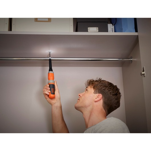 BLACKDECKER BCF603C cordless screwdriver used to fasten screw in closet, orange and black handle visible.