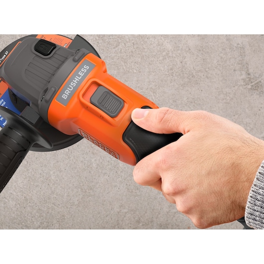 Close-up photo of BLACKDECKER BCG6L8D2S brushless angle grinder handle held by a hand on gray background.