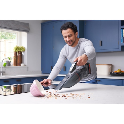 BLACKDECKER BCHV001C1 cordless handheld vacuum cleaning kitchen counter with spilled food and pink bowl.