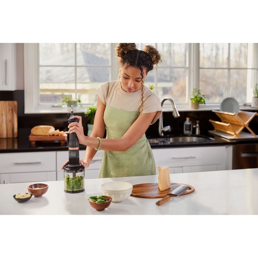 Photo of BLACKDECKER BCKM101FP immersion blender in use, blending greens in a kitchen setting.