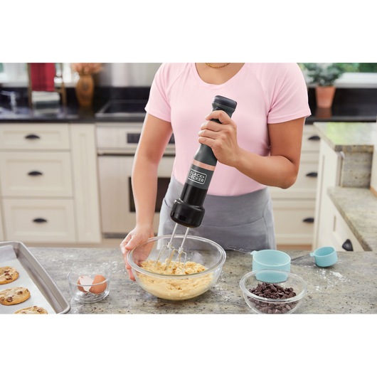 Photo of BLACKDECKER hand mixer BCKM101HM in use mixing cookie dough in a glass bowl on a kitchen counter.