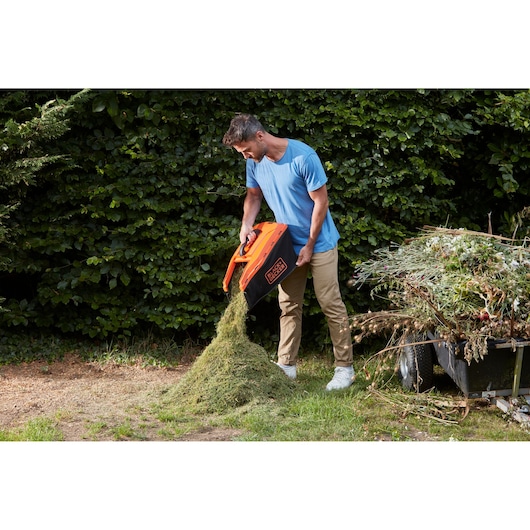 Photo of BLACKDECKER BCMW33184L2 lawn mower grass box being emptied outdoors.