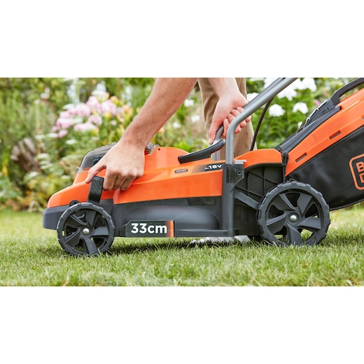 Photo of BLACKDECKER BCMW33184L2 cordless lawn mower, orange and black, side view showing 33cm cutting width.