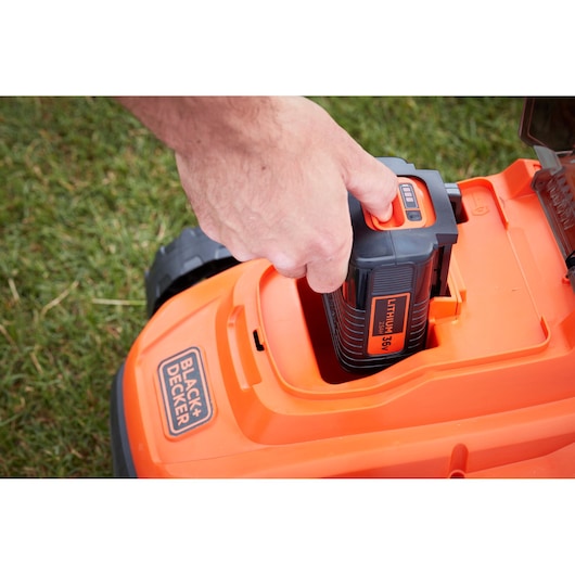 Photo of BLACK+DECKER BCMW3336L2 lawn mower battery compartment with 36V lithium battery being inserted.