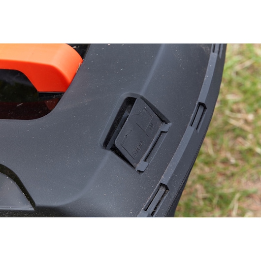 BLACKDECKER BCMW3336N lawn mower control panel close-up showing black plastic stop button, angled view