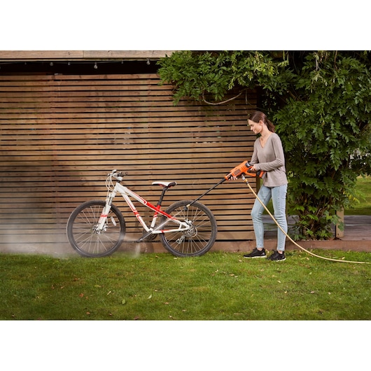 Photo of BLACK+DECKER BCPC18D1 pressure washer being used to clean a mountain bike outdoors.