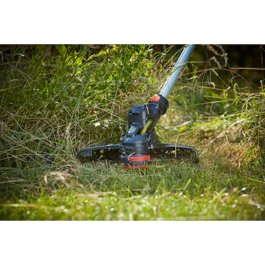 BLACKDECKER BCSTE636L1 grass trimmer cutting tall grass, close-up outdoor view.