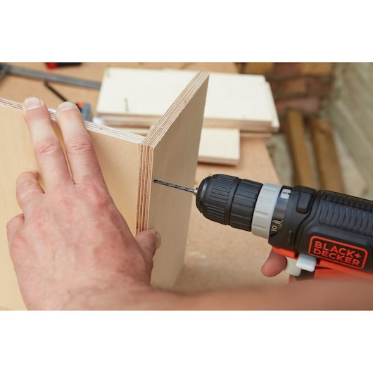 BLACK+DECKER BDCDD12USB cordless drill in use drilling plywood edge, photo of product action.