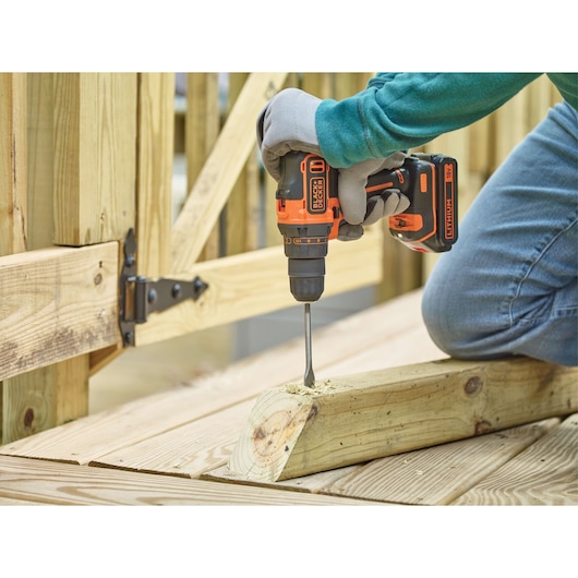 BLACKDECKER BDCDD186KB cordless drill in use on wooden beam, close-up outdoor view.