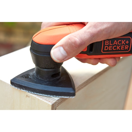 Photo of BLACK+DECKER BDCDS12N sander smoothing plywood edge in close-up view.