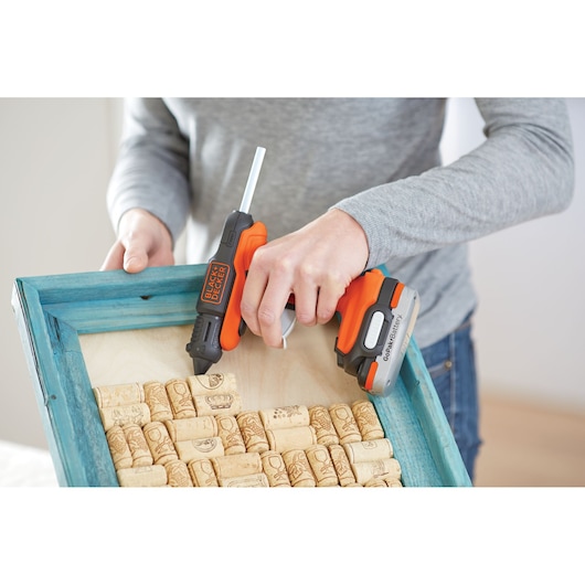 BLACK+DECKER cordless glue gun BDCGG12N used on a wooden frame with corks, close-up