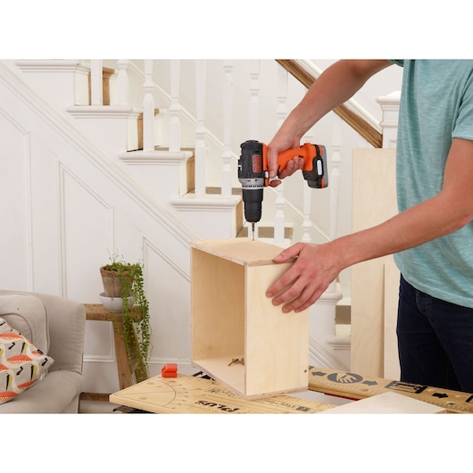 BLACKDECKER BDCHD12S1 cordless drill used for assembling a wooden box indoors.