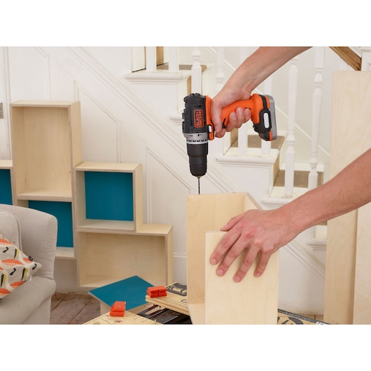 Photo of BLACKDECKER BDCHD12S1 cordless drill being used on wooden boards indoors.