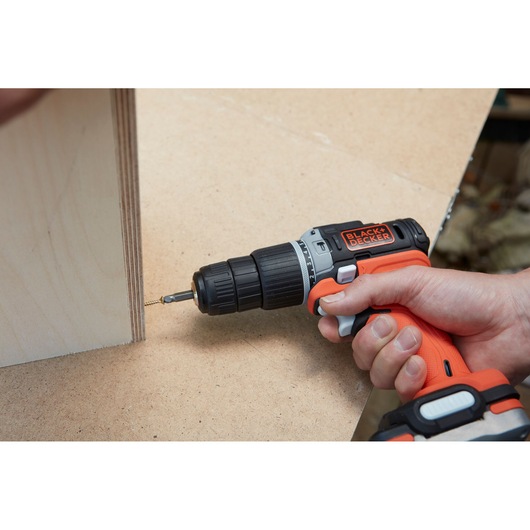 BLACK+DECKER BDCHD12S1 cordless drill driving screw into wood panel, close-up view.