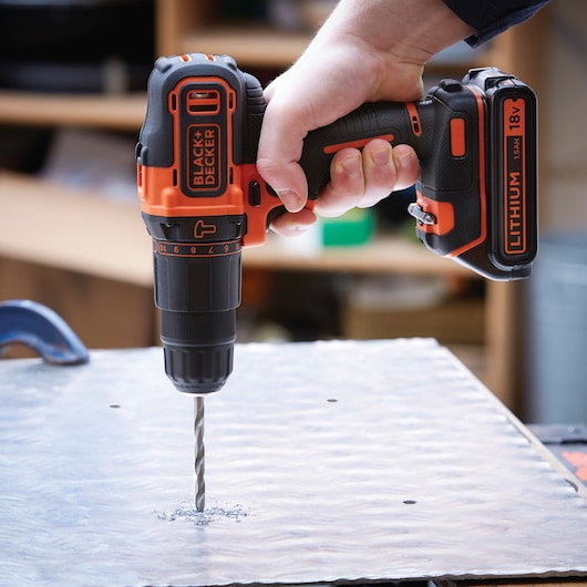 BLACKDECKER BDCHD18S1KA cordless drill being used to drill into a metal sheet, close-up angle.