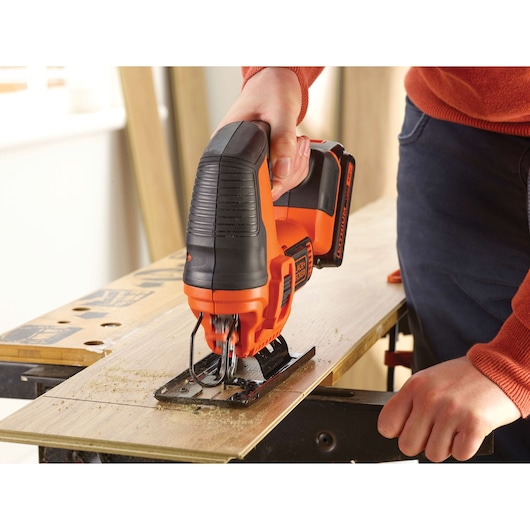 BLACKDECKER BDCJS18 cordless jigsaw cutting wood, shown in use by hand.
