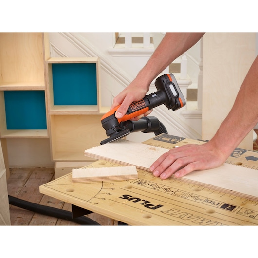 BLACKDECKER BDCK123S2S cordless multi-tool cutting wood on a workbench, close-up angle.
