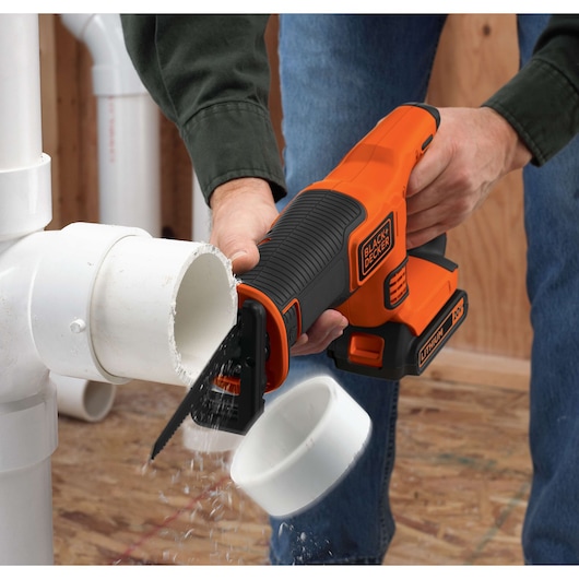 BLACKDECKER BDCR18N cordless reciprocating saw cutting white PVC pipe, close-up action shot.