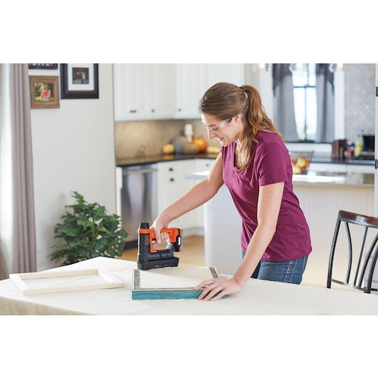 Photo of BLACK+DECKER BDCT12N cordless staple gun used for crafting on a table in a kitchen setting.