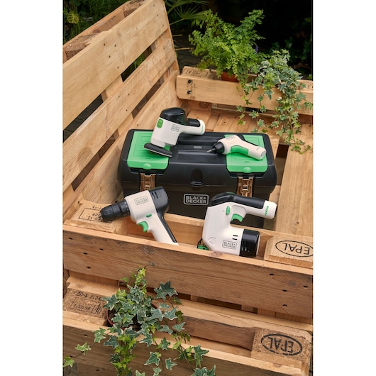 Photo of BLACK+DECKER BDST60120 tool set with black and green toolbox, drill, sander, and screwdriver on wooden crate.