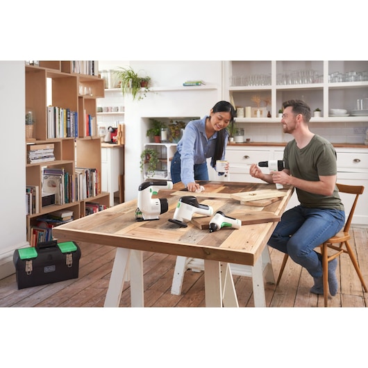 BLACKDECKER BDST60120 white and green power tools on a wooden table in a modern kitchen setting.