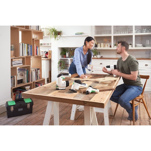 Photo of BLACKDECKER BDST60120 power tools on a wooden table in a modern kitchen, with two people using the tools.