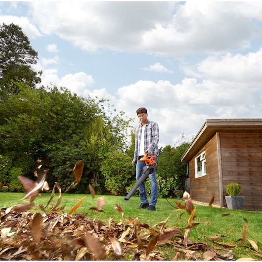 Photo of BLACKDECKER BEBLV260 leaf blower in use outdoors clearing leaves on grass.