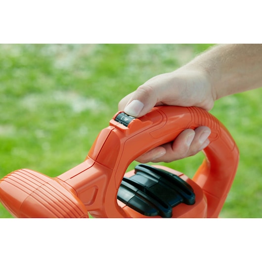 Close-up photo of a hand on the BLACK+DECKER BEBLV290 leaf blower handle with speed control switch.