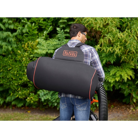 BLACK+DECKER BEBLV300 leaf blower vacuum bag worn on back, black with orange trim, outdoor use.
