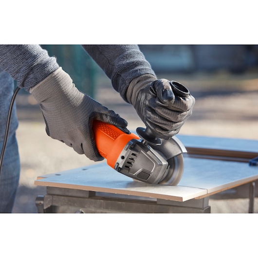 BLACKDECKER BEG110K angle grinder used on tile, close-up, with safety gloves, outdoor workshop.