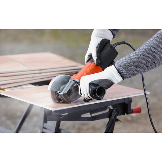 BLACKDECKER BEG110K angle grinder cutting tile, person with gloves holding tool outdoors.