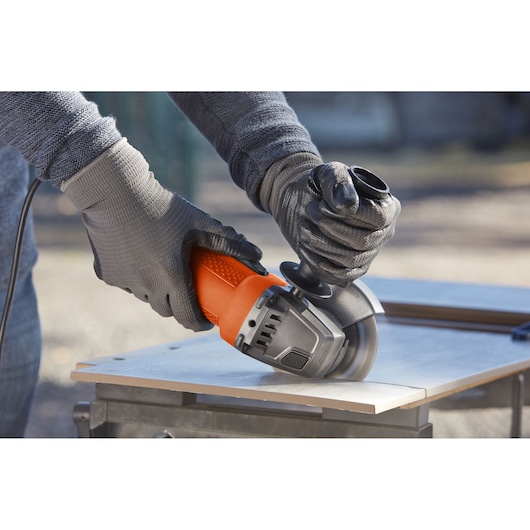 BLACKDECKER BEG110 angle grinder photography showing orange and black tool cutting tile outdoors.
