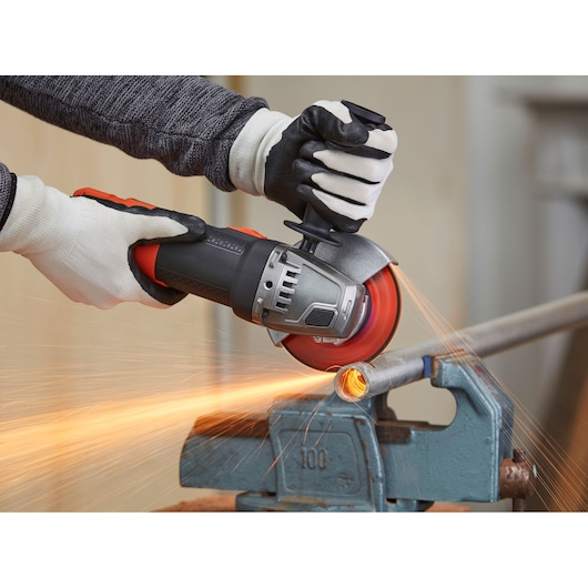 BLACKDECKER BEG220K angle grinder in use cutting metal pipe, sparks flying, photography of product in action.