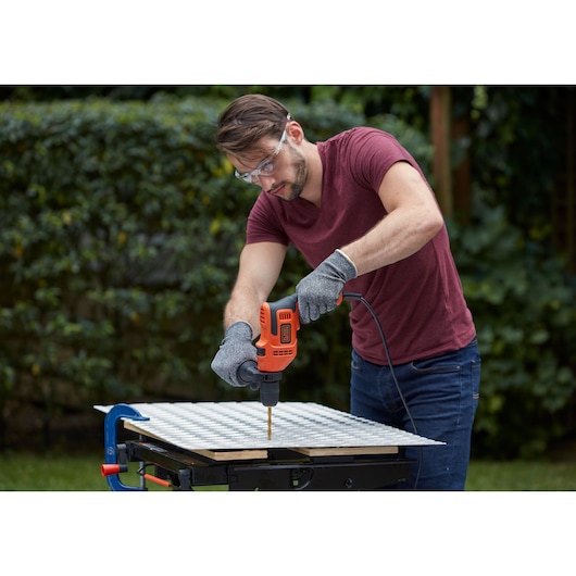 BLACKDECKER BEH200K corded drill used outdoors on metal sheet, person wearing gloves and safety glasses.