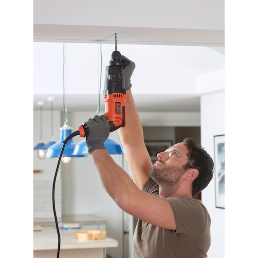 Photo of BLACKDECKER BEHS01 corded hammer drill being used to drill into a ceiling indoors.