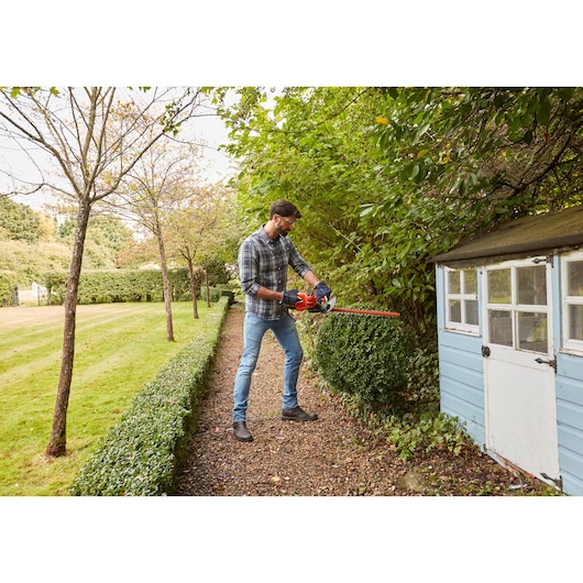BLACKDECKER BEHT251 hedge trimmer in use trimming bushes in a garden