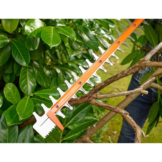 BLACKDECKER BEHTS401 hedge trimmer blade cutting branches in outdoor garden setting.
