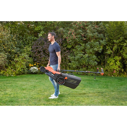 BLACKDECKER BEMW481ES lawn mower carried by a person in a garden, orange and black design.
