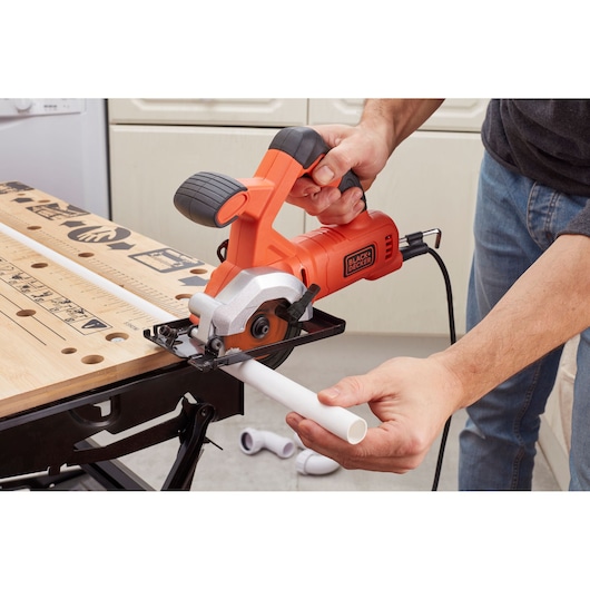 Photo of BLACKDECKER BES510K compact circular saw cutting a white plastic pipe on a workbench.