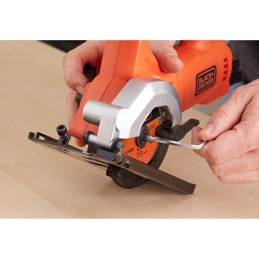Photo of BLACK+DECKER BES510K compact circular saw being adjusted with hex key on wooden surface.