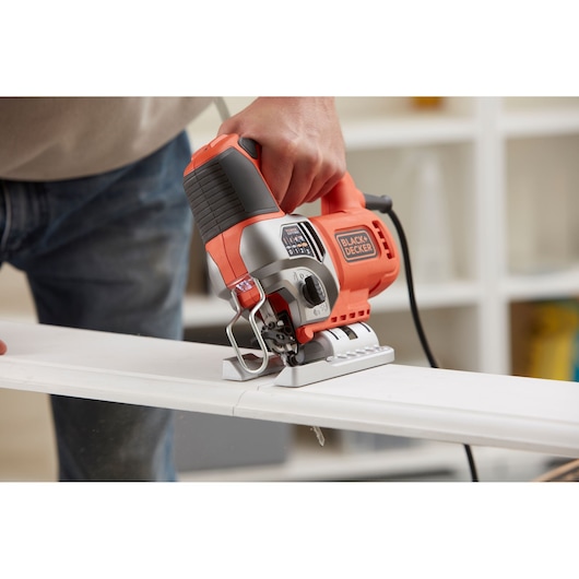 BLACK+DECKER BES610 jigsaw in use cutting wood, close-up photography showing ergonomic handle.
