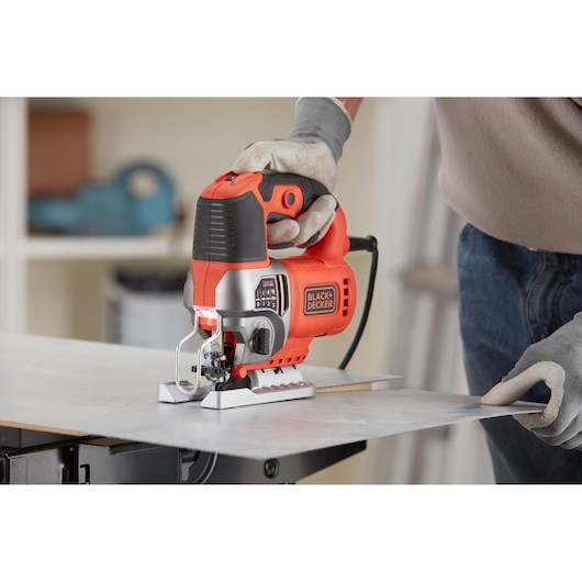 BLACK+DECKER BES610 jigsaw used for cutting sheet material, close-up view in workshop setting.