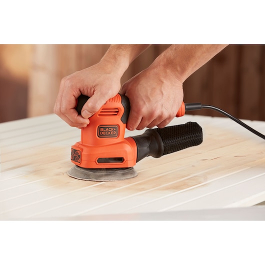 Photo of BLACK+DECKER BEW200 orange electric sander being used on light wood surface.