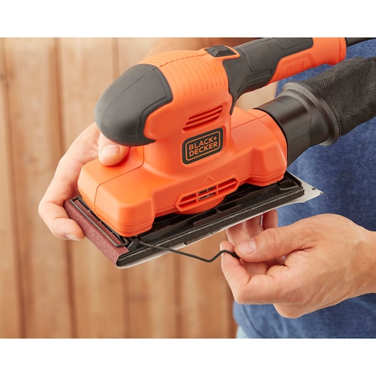 Photo of BLACKDECKER BEW220 sheet sander held by hands, close-up showing sanding pad attachment.